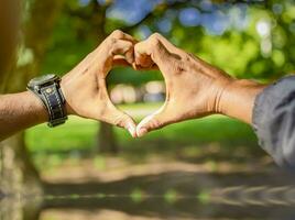 dichtbij omhoog van twee handen samen in een hart vorm geven aan, handen samen in een hart vorm geven aan, jong Mens zetten vingers samen in een hart vorm foto