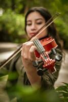 levensstijl van meisje met haar viool spelen een melodie buitenshuis, concept van glimlachen vrouw violist. Latijns meisje spelen de viool buitenshuis. portret van een Latijns meisje spelen de viool buitenshuis foto