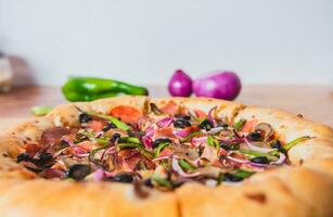 opperste pizza met olijven en groenten Aan houten tafel met ruimte voor tekst. heerlijk opperste pizza met groenten geserveerd Aan tafel foto