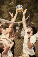 groep van jong vrienden spelen strand volleybal foto