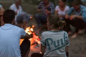 jong vrienden ontspannende in de omgeving van kampvuur foto