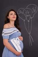 portret van zwanger vrouw in voorkant van zwart schoolbord foto