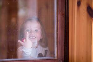 weinig schattig meisje spelen in de buurt de venster foto