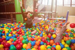 jong mam spelen met kinderen in zwembad met kleurrijk ballen foto