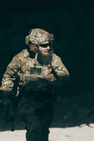 een gebaard soldaat in uniform van speciaal krachten in een gevaarlijk leger actie in een gevaarlijk vijand Oppervlakte. selectief focus foto