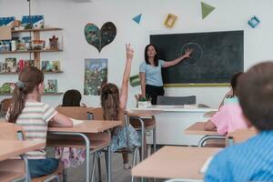 elementair school. de vrouw leraar helpen de kind leerling terwijl schrijven de antwoord Aan de schoolbord. foto