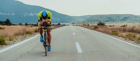 vol lengte portret van een actief triatleet in sportkleding en met een beschermend helm rijden een fiets. selectief focus foto