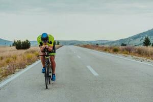 vol lengte portret van een actief triatleet in sportkleding en met een beschermend helm rijden een fiets. selectief focus foto