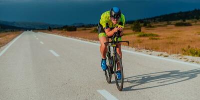 vol lengte portret van een actief triatleet in sportkleding en met een beschermend helm rijden een fiets. selectief focus foto