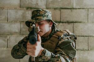 een soldaat in uniform staat in voorkant van een steen muur in vol oorlog uitrusting voorbereidingen treffen voor strijd foto