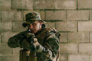 een soldaat in uniform staat in voorkant van een steen muur in vol oorlog uitrusting voorbereidingen treffen voor strijd foto