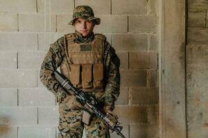 een soldaat in uniform staat in voorkant van een steen muur in vol oorlog uitrusting voorbereidingen treffen voor strijd foto