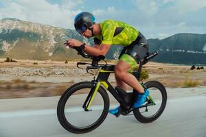 vol lengte portret van een actief triatleet in sportkleding en met een beschermend helm rijden een fiets. selectief focus foto