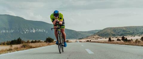 vol lengte portret van een actief triatleet in sportkleding en met een beschermend helm rijden een fiets. selectief focus foto