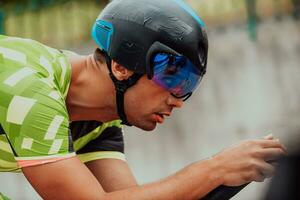 dichtbij omhoog foto van een actief triatleet in sportkleding en met een beschermend helm rijden een fiets. selectief focus