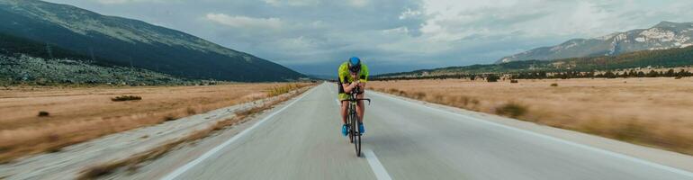 vol lengte portret van een actief triatleet in sportkleding en met een beschermend helm rijden een fiets. selectief focus foto