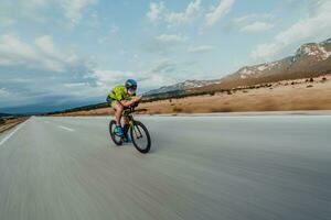 vol lengte portret van een actief triatleet in sportkleding en met een beschermend helm rijden een fiets. selectief focus foto