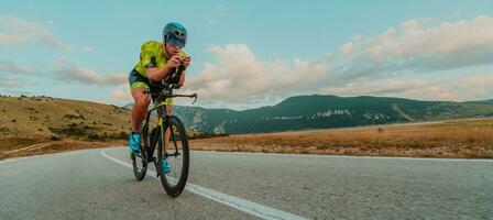 vol lengte portret van een actief triatleet in sportkleding en met een beschermend helm rijden een fiets. selectief focus foto