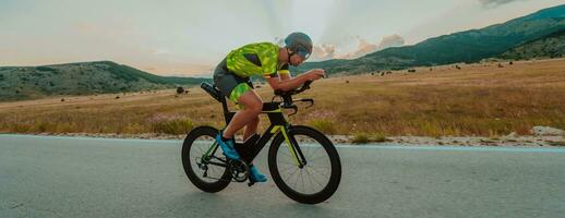 vol lengte portret van een actief triatleet in sportkleding en met een beschermend helm rijden een fiets. selectief focus foto