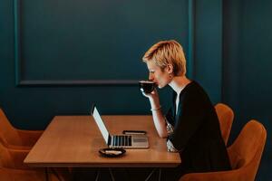 zakenvrouw zittend in koffie winkel Bij houten tafel, drinken koffie en gebruik makend van laptop. zakenvrouw browsen internetten, chatten, bloggen. selectief focus foto