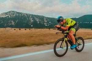 vol lengte portret van een actief triatleet in sportkleding en met een beschermend helm rijden een fiets. selectief focus foto