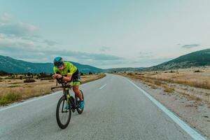 vol lengte portret van een actief triatleet in sportkleding en met een beschermend helm rijden een fiets. selectief focus foto