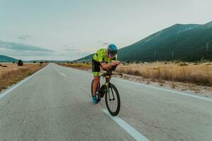 vol lengte portret van een actief triatleet in sportkleding en met een beschermend helm rijden een fiets. selectief focus foto