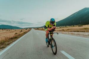 vol lengte portret van een actief triatleet in sportkleding en met een beschermend helm rijden een fiets. selectief focus foto