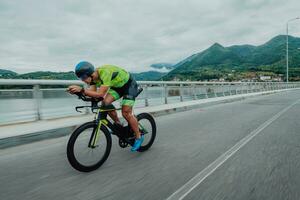 vol lengte portret van een actief triatleet in sportkleding en met een beschermend helm rijden een fiets. selectief focus foto