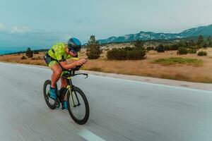 vol lengte portret van een actief triatleet in sportkleding en met een beschermend helm rijden een fiets. selectief focus foto