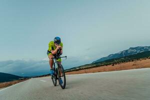 vol lengte portret van een actief triatleet in sportkleding en met een beschermend helm rijden een fiets. selectief focus foto