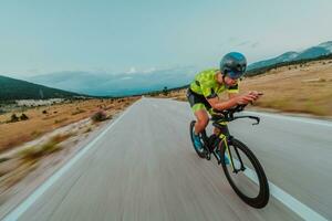 vol lengte portret van een actief triatleet in sportkleding en met een beschermend helm rijden een fiets. selectief focus foto