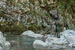 een leger Mens of airsoft speler in een camouflage pak sluipen de rivier- en doelen van een scherpschutter geweer- naar de kant of naar doelwit. foto