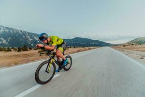 vol lengte portret van een actief triatleet in sportkleding en met een beschermend helm rijden een fiets. selectief focus foto