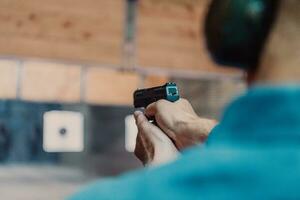 een Mens praktijken het schieten een pistool in een het schieten reeks terwijl vervelend beschermend hoofdtelefoons foto