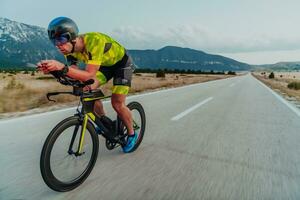 vol lengte portret van een actief triatleet in sportkleding en met een beschermend helm rijden een fiets. selectief focus foto