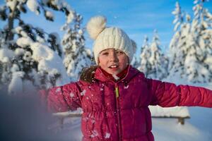 meisje het werpen vers sneeuw Bij mooi zonnig winter dag foto