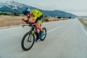 vol lengte portret van een actief triatleet in sportkleding en met een beschermend helm rijden een fiets. selectief focus foto