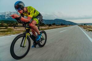 vol lengte portret van een actief triatleet in sportkleding en met een beschermend helm rijden een fiets. selectief focus foto