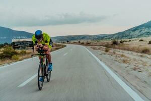 vol lengte portret van een actief triatleet in sportkleding en met een beschermend helm rijden een fiets. selectief focus foto