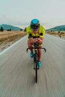 vol lengte portret van een actief triatleet in sportkleding en met een beschermend helm rijden een fiets. selectief focus foto