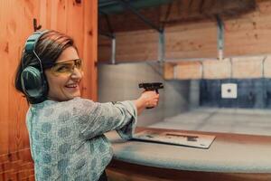 een vrouw praktijken het schieten een pistool in een het schieten reeks terwijl vervelend beschermend hoofdtelefoons foto