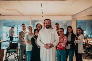 een verschillend groep van geslaagd bedrijf mensen in een modern glas kantoor staan samen Bij de top met hun Arabisch leider regisseur foto