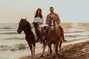 een liefhebbend paar in zomer kleren rijden een paard Aan een zanderig strand Bij zonsondergang. zee en zonsondergang in de achtergrond. selectief focus foto