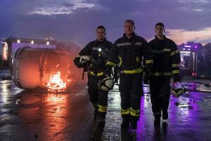 dapper brandweerlieden team wandelen naar de camera. in achtergrond paramedici en brandweer redden team strijd brand in auto ongeluk, verzekering en opslaan volkeren leeft concept. foto