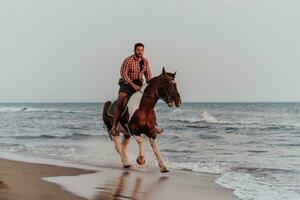 een modern Mens in zomer kleren geniet rijden een paard Aan een mooi zanderig strand Bij zonsondergang. selectief focus foto