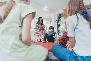 lezing tijd in een elementair school- of kleuterschool, een leraar leest een boek naar kinderen in een elementair school- of kleuterschool. de concept van peuter onderwijs. selectief focus foto