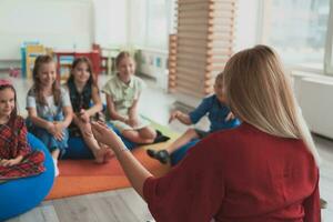 lezing tijd in een elementair school- of kleuterschool, een leraar leest een boek naar kinderen in een elementair school- of kleuterschool. de concept van peuter onderwijs. selectief focus foto