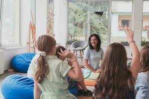 lezing tijd in een elementair school- of kleuterschool, een leraar leest een boek naar kinderen in een elementair school- of kleuterschool. de concept van peuter onderwijs. selectief focus foto