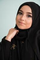 mooi moslim vrouw in modieus jurk met hijab geïsoleerd Aan modern cyaan achtergrond vertegenwoordigen concept van modern Islam en Ramadan kareem foto